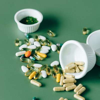 Variety of supplements and pills scattered on a green background, showcasing modern medicine concepts.